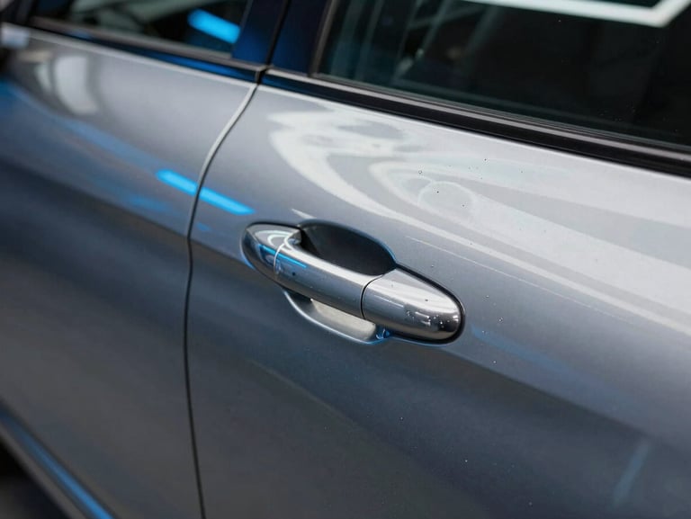 Close-up of a perfectly polished metallic car door showing a sharp, mirror-like reflection of neon blue workshop lights