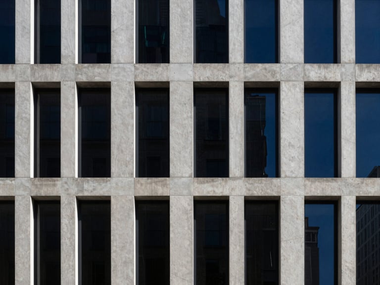 Minimalist modern concrete skyscraper facade in New York, sharp high-contrast afternoon sunlight, deep shadows, architectural crop