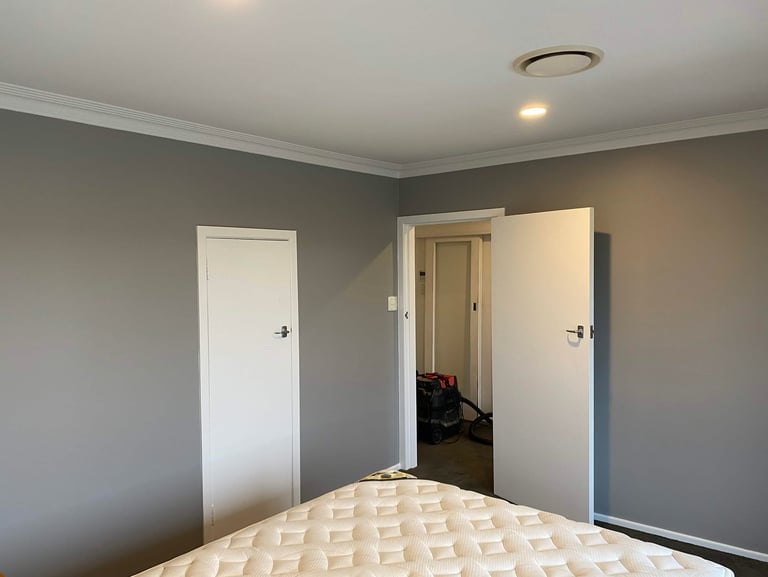 Freshly painted gray bedroom walls with white trim, open doors, and a mattress in the foreground.