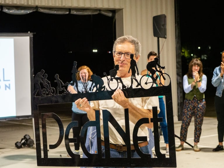 Man holding a metal "PedNet" logo sign