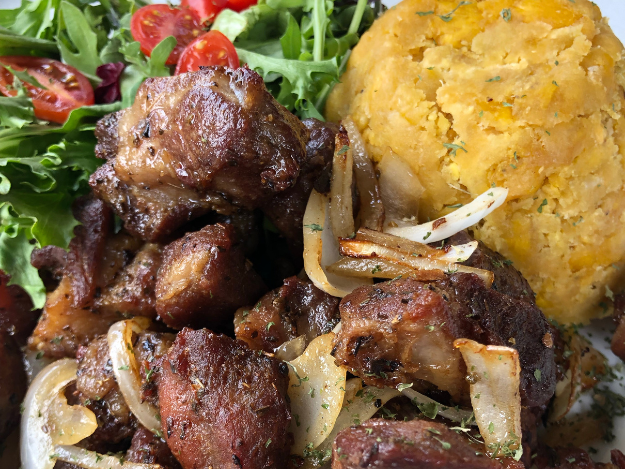 a plate of carne frita con mofongo and vegetables