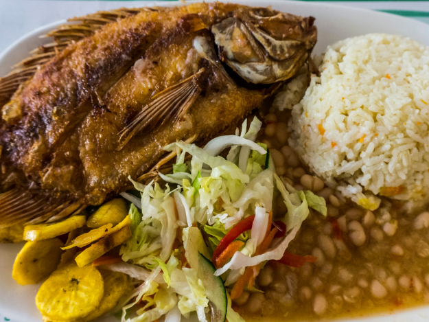 a plate of food with beans, white rice and fried fish