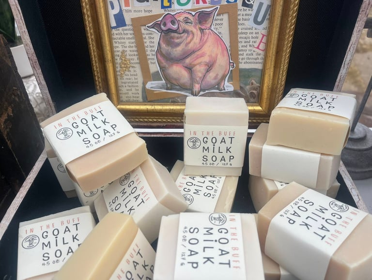 A stack of In the lard soap bars in front of a framed pig illustration.