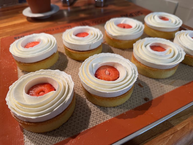 a tray of cupcakes with strawberries and cream