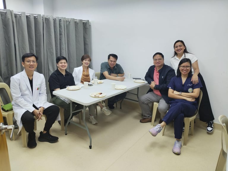 A group of Filipino doctors and medical professionals smiling while gathered around a table for a meeting.