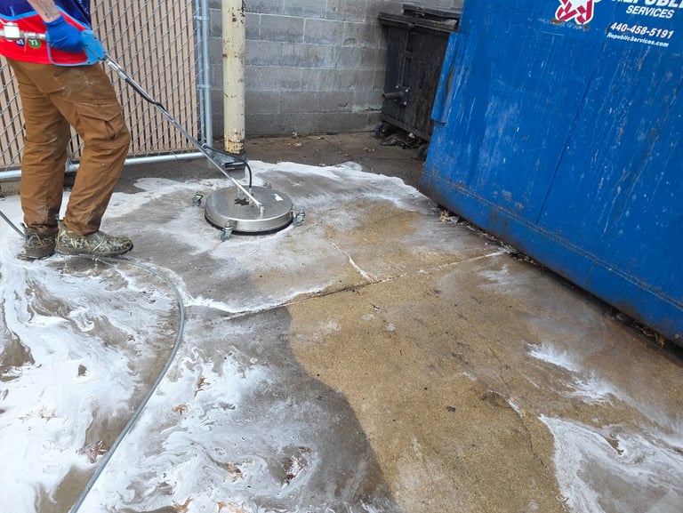 Pressure washing of a dirty dumpster enclosure