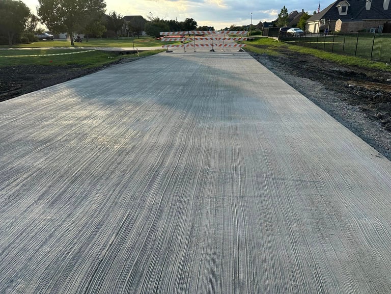 Freshly poured concrete road with barricades ahead.