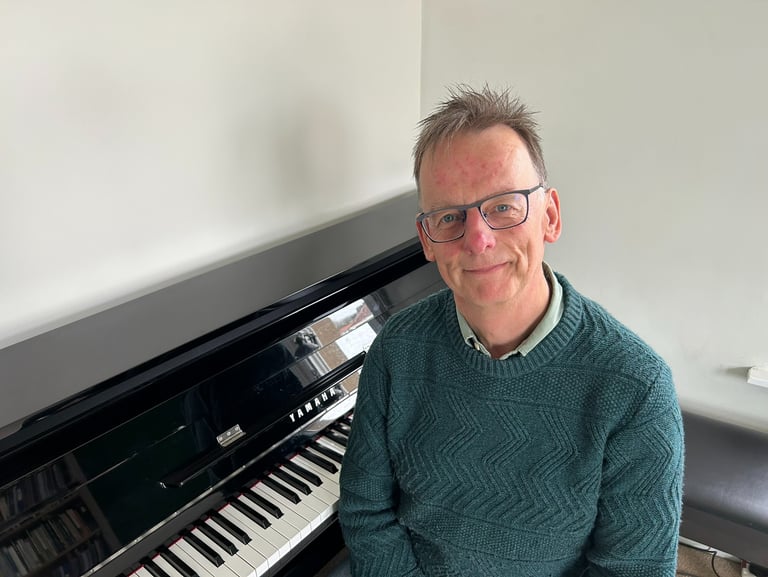 Photo of Steven with a piano behind him