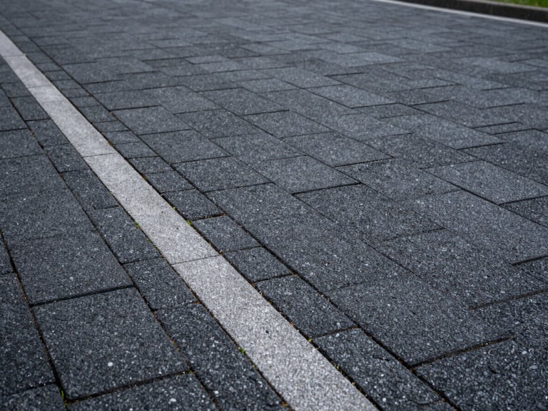 A beautifully paved driveway with anthracite interlocking stones, perfect drainage channels on the side, clean edges.