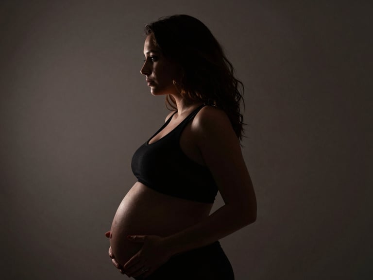 Dramatic silhouette of a pregnant woman, hard side lighting, deep chiaroscuro.