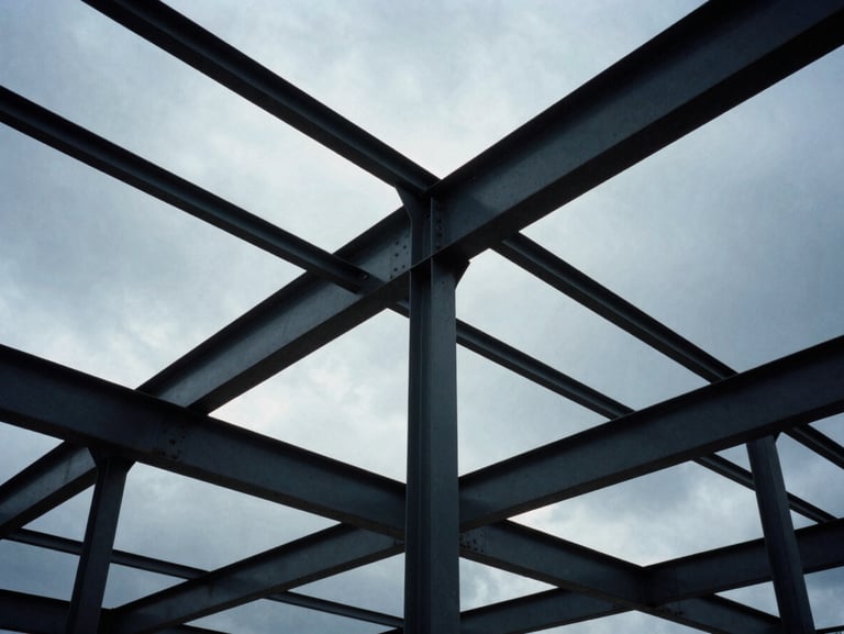 Low-angle heroic shot of structural steel frameworks against a dramatic overcast sky, cool industrial tones, 35mm film