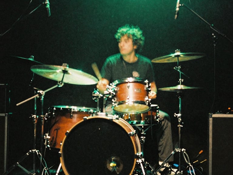 Gritty, motion-blurred shot of a drum kit on a dark stage under electric neon green lighting flares, 35mm film.