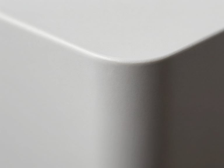 Extreme macro close-up of a perfectly curved solid surface corner joint, flawless white matte texture, dramatic side lighting highlighting the seamless transition.