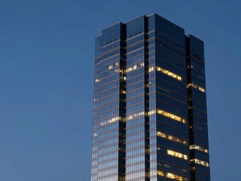 High-contrast architectural perspective of a modern corporate tower in Miami against a deep blue evening sky, warm interior lights reflecting on glass, clean lines, negative space on the left.