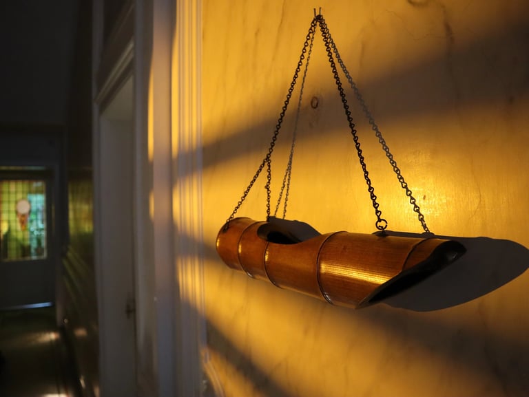 A vintage hanging bamboo planter suspended by metal chains on a textured wall with warm mood lighting.