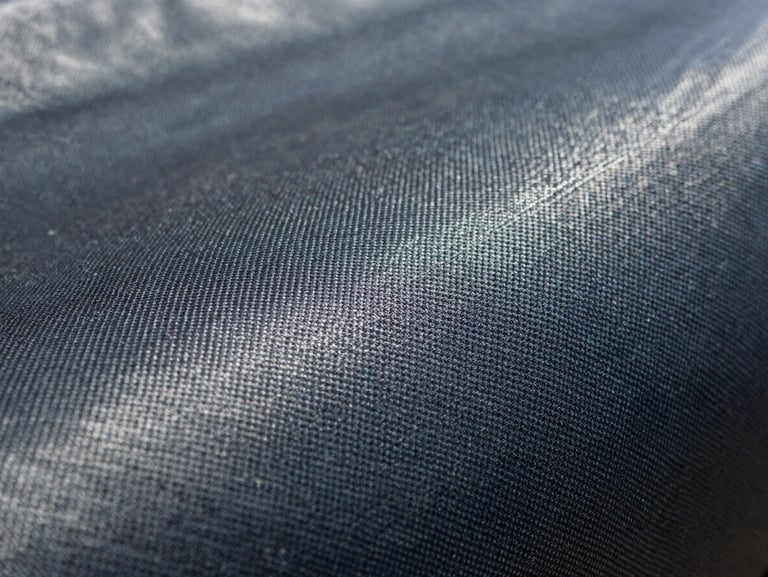 Extreme macro shot of UV-stabilized agricultural ground cover fabric, highlighting the tight fiber density and puncture-resistant weave under direct daylight.