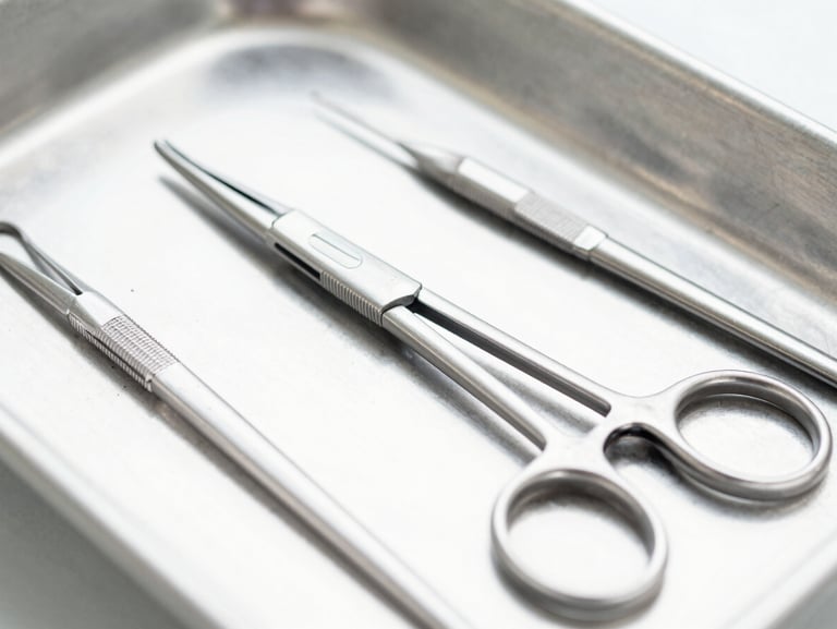 Macro shot of sterile surgical forceps and clamps on a clean metal tray, bright clinical lighting