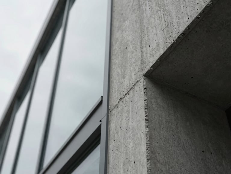 Extreme close-up architectural detail of raw concrete meeting structural glass, low-angle overcast diffuse daylight, focusing on material intersection