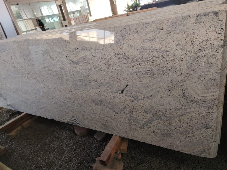 Polished slab of white wave granite with grey veining for custom kitchen countertops and flooring.