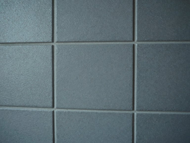 Close-up of a tiled wall section with textured matte finish, grout lines precise and even, cool diffused studio light emphasising surface relief and material consistency, no people