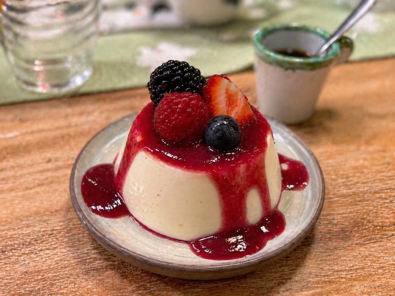 Creamy vanilla panna cotta dessert topped with berry coulis, fresh strawberries, and blackberries.