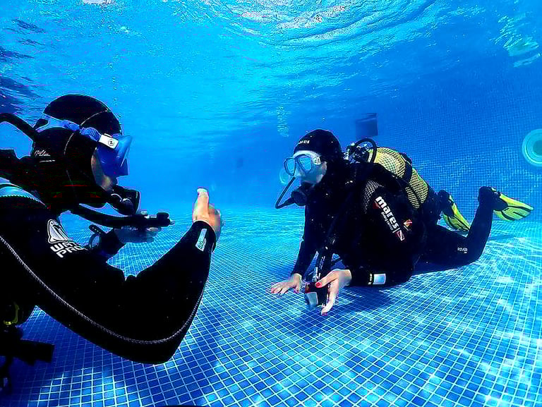 Scuba diving instructor teaching a beginner underwater during a try dive in Funchal, Madeira