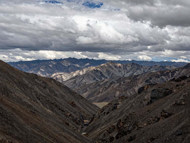 Wide environmental shot of the Wind River Range in overcast, dramatic light, low-contrast natural daylight with deep valleys and rocky peaks.