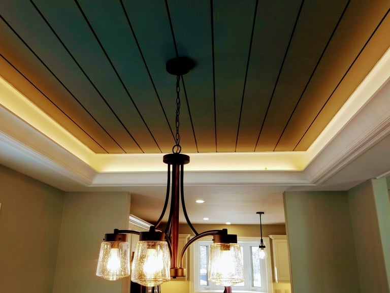 Modern bronze chandelier with seeded glass shades hanging from a tray ceiling with cove lighting.
