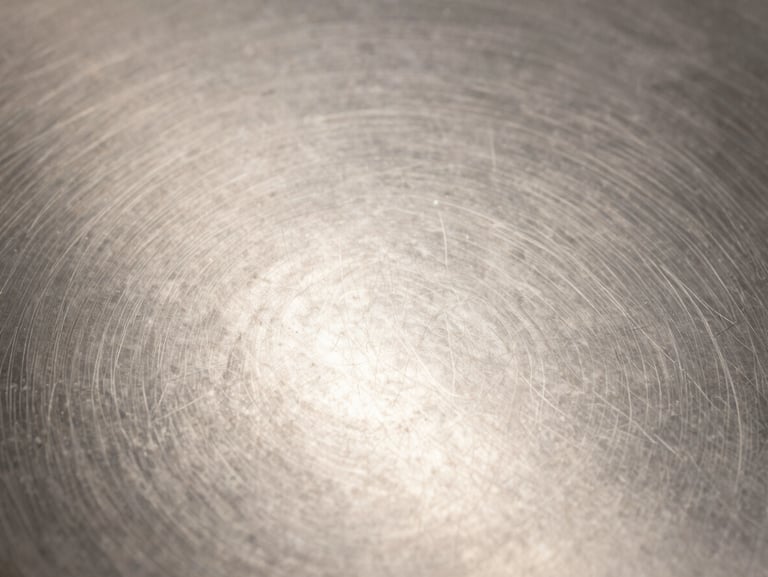 A close-up macro shot of an immaculate, streak-free stainless steel surface under bright, clean studio lighting with zero warm filters.