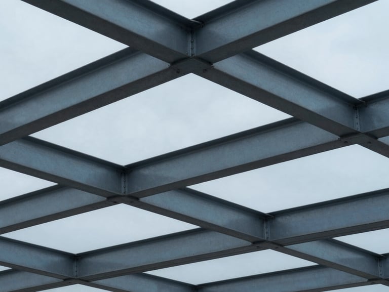 Tight abstract architectural crop of structural steel beams reflecting cool overcast light, desaturated blue tones