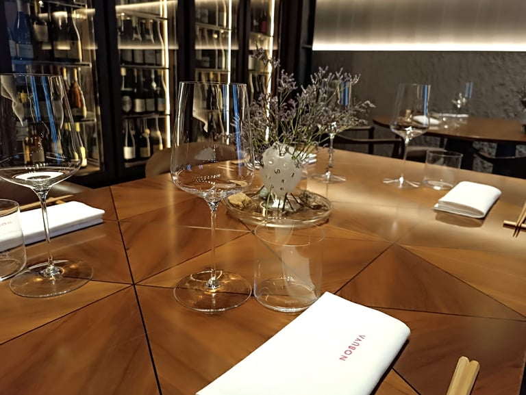 Sala del ristorante Nobuya Milano con tavolo apparecchiato e cantina a vista sullo sfondo