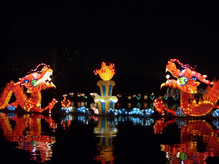 Illuminated Chinese dragon lanterns reflecting on water during a traditional Mid-Autumn Festival display.