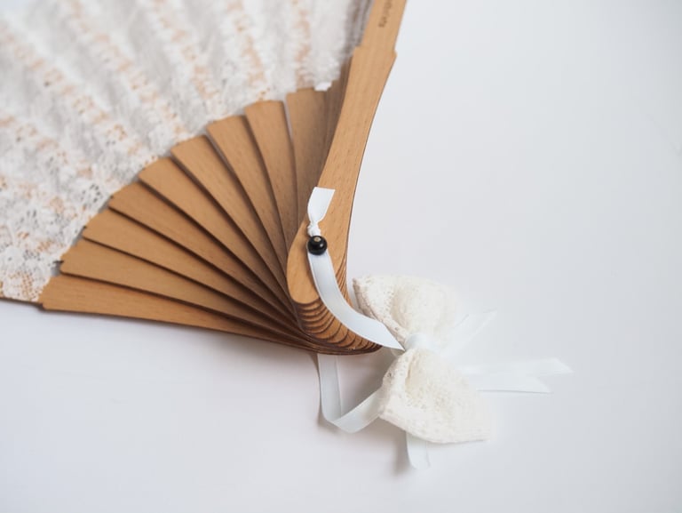 a white lace covered wooden hand fan 