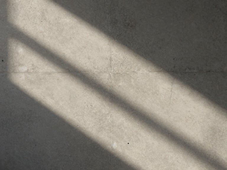 Soft abstract play of light and shadow on a light warm gray concrete wall, quiet and atmospheric