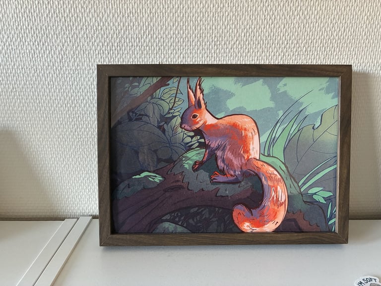 Framed illustration of a red squirrel sitting on a mossy branch in a forest.