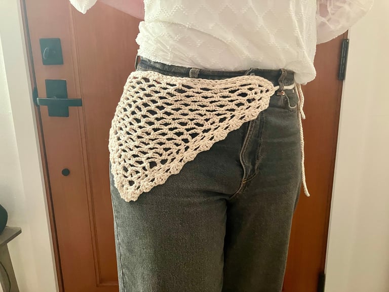 Model wearing crochet bandana belt wrapped around waist of jeans