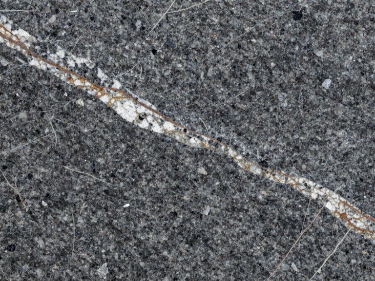 Macro texture of polished deep grey granite slab with rich white and terracotta veining, high contrast, structural detail.