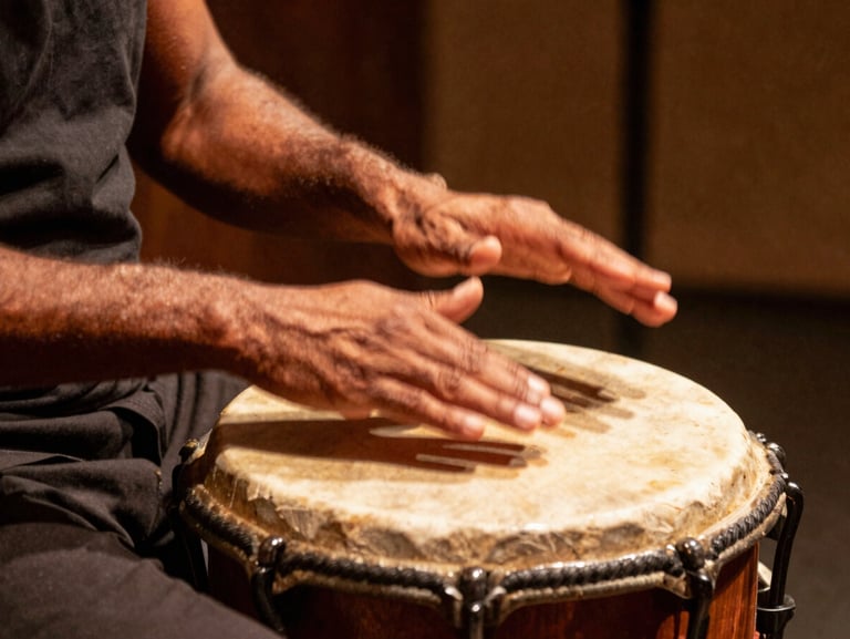 Tight crop of expressive hands striking an atabaque drum, warm stage spotlight, motion blur on the hands, rich golden and earthy tones.