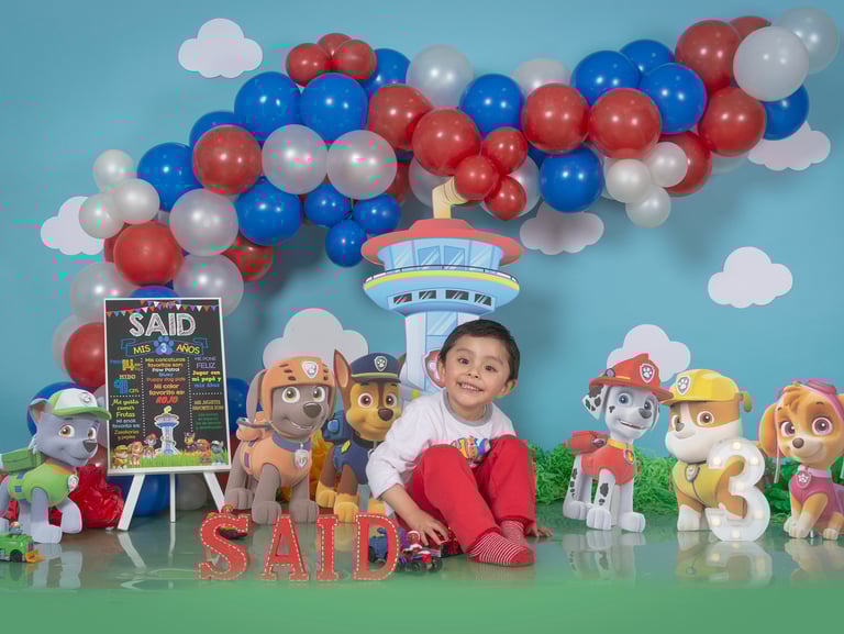a young boy sitting on a table with balloons and balloons