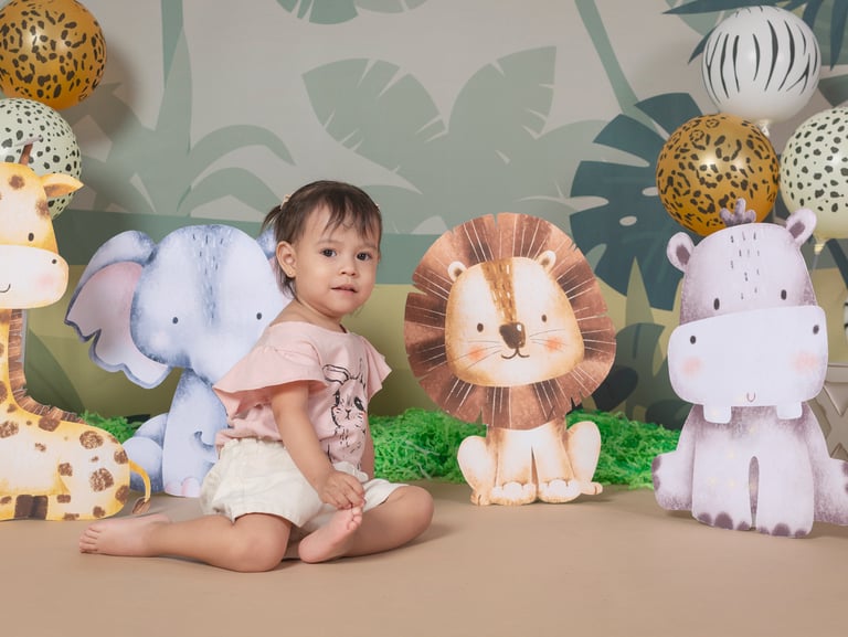 a baby girl sitting on a table with a bunch of stuffed animals