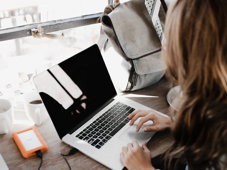 a woman sitting at a desk with a laptop, writing a blog and creating content for brands
