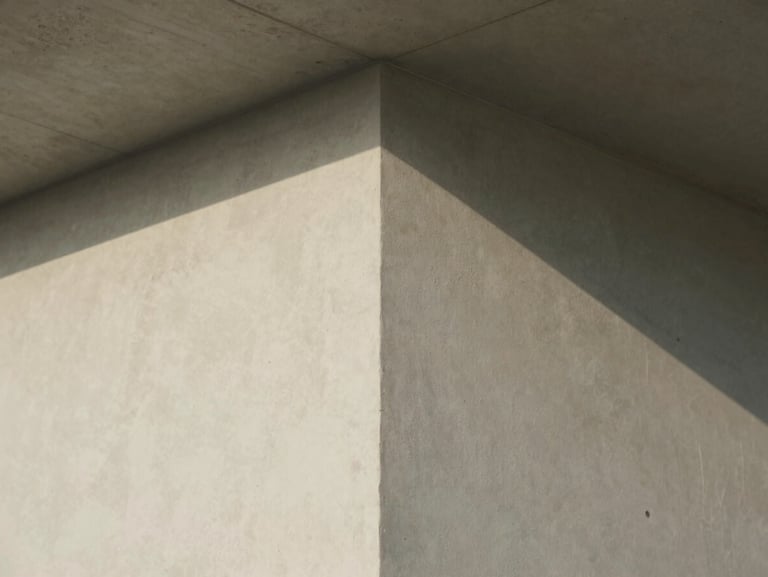 Straight-on architectural detail of a plaster wall meeting a concrete ceiling joint, soft directional daylight, clean lines.