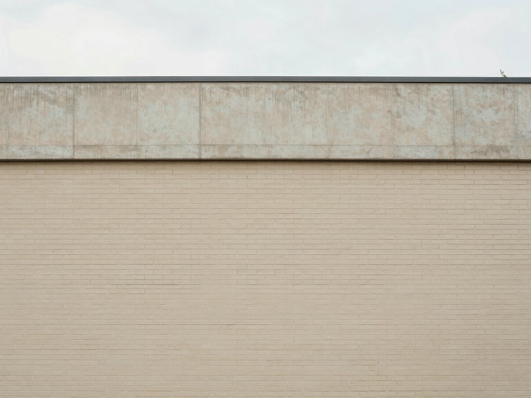 Straight-on architectural detail of clean brick and concrete building facade, soft natural overcast daylight, minimal composition, 35mm lens