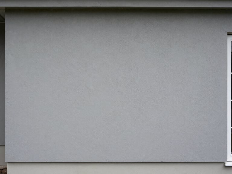 Freshly applied grey stucco foundation cladding on a residential exterior, even texture, clean bottom edge, natural overcast daylight, wide framing