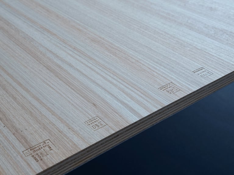 Close-up of structural plywood sheet showing natural wood grain texture and stamped Australian standard certification codes, overcast daylight