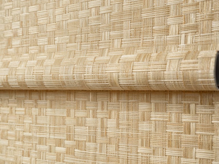 Close-up detail shot of woven roller blind fabric texture, soft north-facing daylight catching the weave pattern, warm cream and sand tones, no people, tight macro framing showing individual fabric threads and the way light filters through the material, landscape aspect