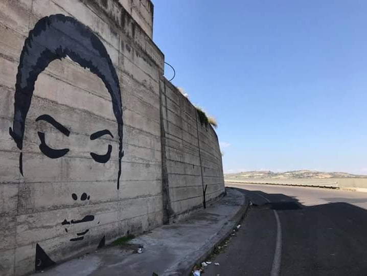 Stylized female face painted on concrete wall, urban artwork by Poliops.