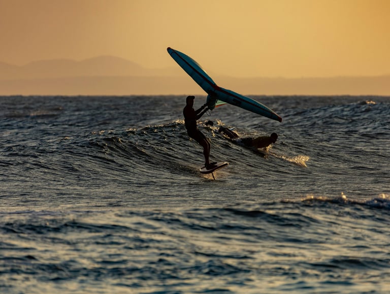Wingfoil surfing on a wave during sunset