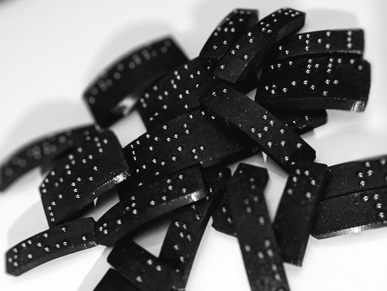 Plaque en braille, empilée de manière aléatoire, avec des points en relief bien visible