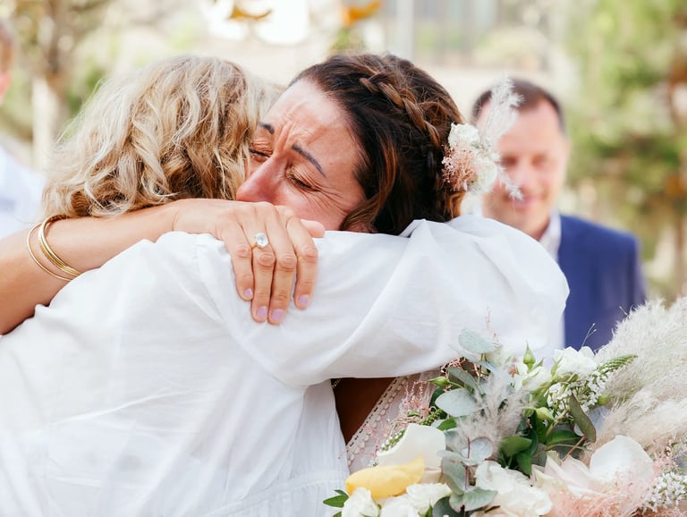 Photographie de mariée qui pleure de bonheur en serrant dans ses bras sa mère après la cérémonie de mariage, Talmont, Vendée